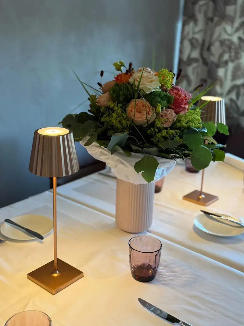 Gedeckter Tisch mit Tischlampe und Blumenstrauß